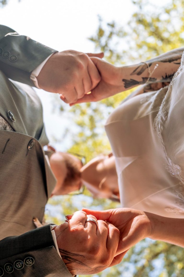 Das Gelübde: Muss ich wirklich etwas vor allen sagen? Ein Hochzeitspaar, dass sich küsst und sich an den Händen hält. Dabei ist die Kameraperspektive von unten nach oben.