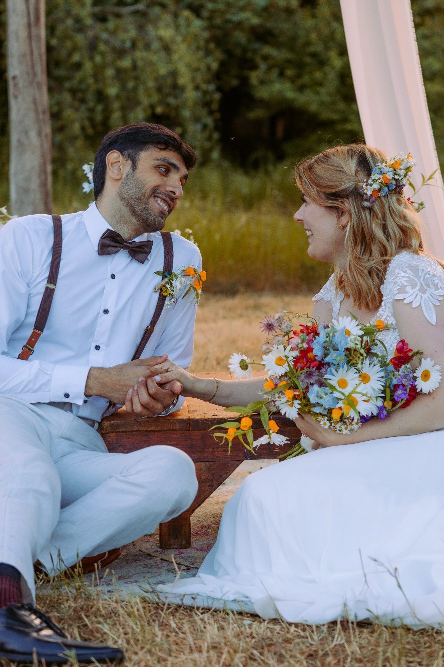 After Wedding-Moment Braut schaut lachend zu Bräutigam. Beide halten Händchen und schauen sich in die Augen.