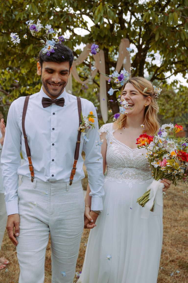 Brautpaar steht im Freien. Er drückt sie mit seiner rechten Hand ihren Kopf an seinen, so dass sich Stirn und Nase berühren.